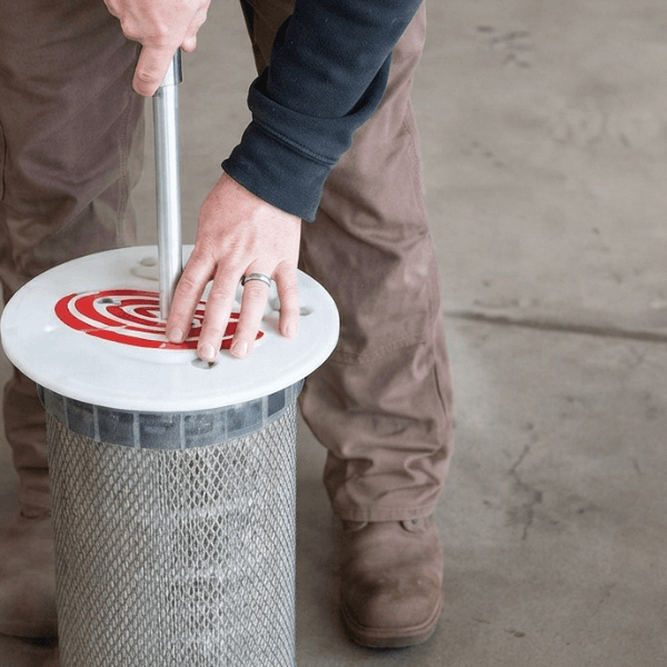 A man cleans a filter using a hose, directing water to remove debris and ensure proper functionality.