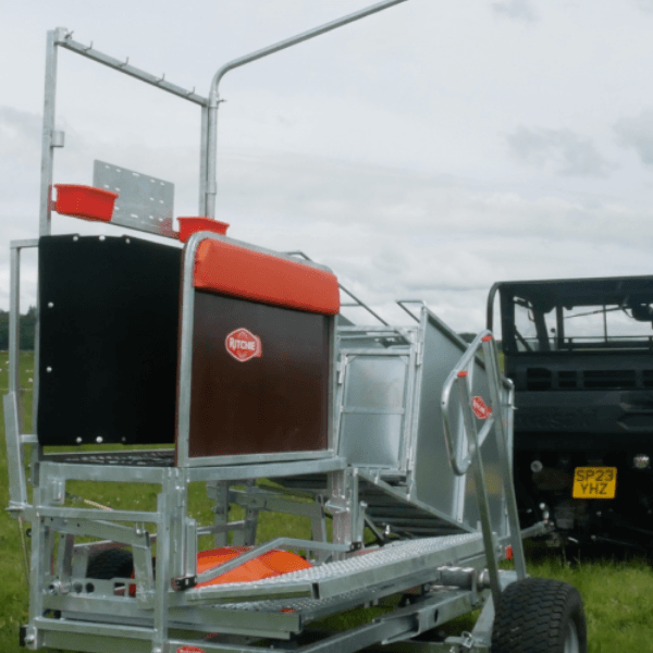 A tractor pulling a trailer in a green field, showcasing agricultural activity and rural landscape.